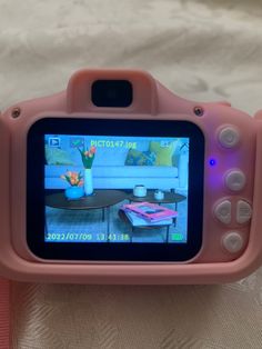 a pink digital camera sitting on top of a bed