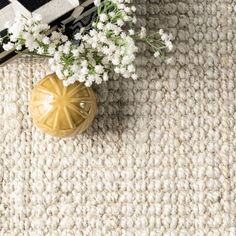 a vase filled with white flowers sitting on top of a rug