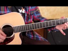 a man is playing an acoustic guitar while sitting down with his hands on the strings