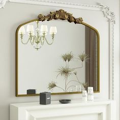 a white mantle with a mirror and candles on it in front of a fire place