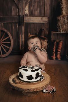 a baby sitting in front of a cake on top of a wooden table and eating it