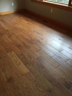 an empty room with hard wood flooring and windows in the corner, looking out