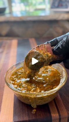 a person dipping food into a bowl on top of a wooden table