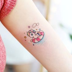 a small tattoo on the arm of a girl with an unicorn and stars around her neck