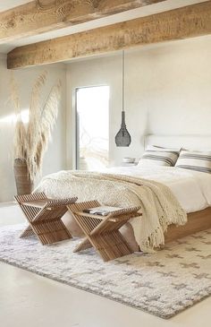 a bedroom with a bed, two chairs and a rug on the floor in front of it