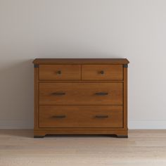 a wooden dresser sitting on top of a hard wood floor next to a white wall