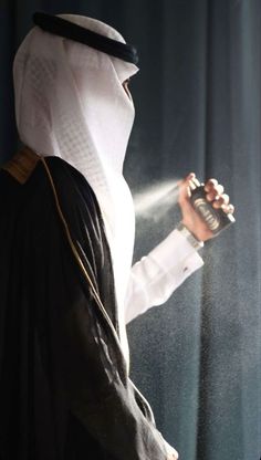 a man in a white and black outfit spraying water on his face with a sprayer