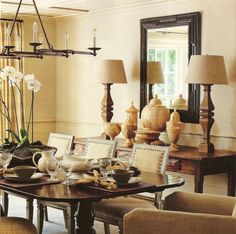 a dining room table with chairs and plates on it in front of a large mirror