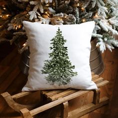 a christmas tree pillow sitting on top of a wooden chair next to a potted plant