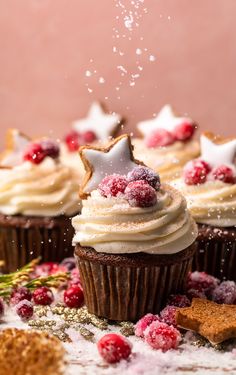 cupcakes with icing and sprinkles are on a table covered in snow