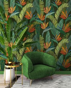 a green chair sitting next to a plant in front of a wall with leaves on it