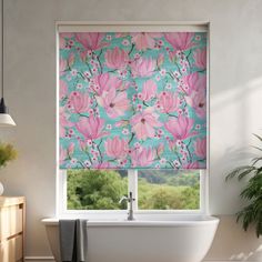 a bathroom window with pink flowers on the roller shades in front of it and a tub