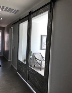 an empty hallway with sliding glass doors leading to another room and a chair on the other side