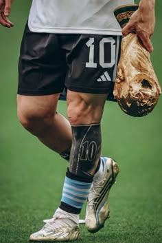 a soccer player with his foot in the air holding a ball and wearing a gold glove