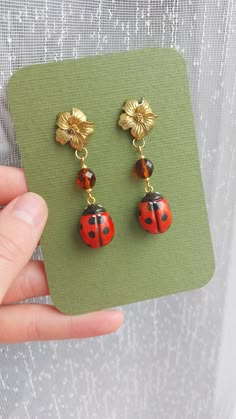 Handmade ladybug earrings, for someone who likes unusual jewelry. Ladybug is handmade from polymer clay and hand-painted. Cute golden flower together with brown glass bead creates vintage and earthy look. Length from the hook: 5.5 cm / 2.17 inches.  Earrings will arrive packed in cute decorative paper, so you will be able to gift them without the need for additional gift wrapping. Disinfect the hook before wearing. CARE INSTRUCTIONS:  Do not keep your earrings in direct sunlight as it may affect the metal color. Be gentle with your earrings; avoid playing with them or pulling on them. Do not bathe while wearing your earrings; keep them away from water. Keep earrings in a dry, shaded place. Keep each pair of earrings separate from each other because different types of metals can react, pote Polymer Clay Bug Earrings, Clay Earrings Air Dry, Polymer Clay Snail, Clay Ladybug, Bug Earrings, Ladybug Earrings, Bug Jewelry, Cute Ladybug, Unusual Earrings