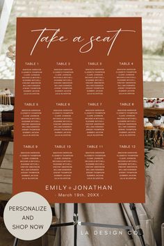 an orange and white wedding seating sign with the names of each seat on it, in front of a wooden table