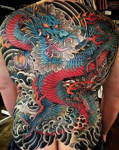 the back of a man's body covered in tattoos with dragon designs on it