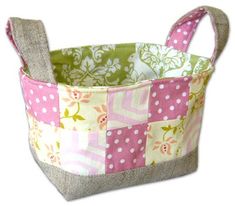 a pink and green patchwork fabric storage basket with handles on the side, filled with small white polka dots