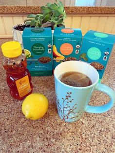 a cup of coffee sitting on top of a counter next to some honey and lemons