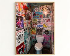 there is a toilet with many stickers on the wall in this bathroom that has graffiti all over it