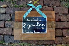 a wooden sign that says to plant a garden is better in tomorrow on brick wall