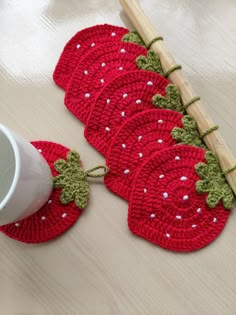 crocheted coasters with strawberries on them sitting next to a coffee cup