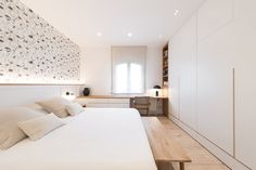 a white bed sitting in a bedroom next to a wooden desk and bookcases