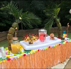 an inflatable pool with pineapples, drinks and decorations on the table