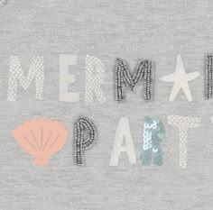 the words mermaid party are made out of letters and seashells on a gray shirt