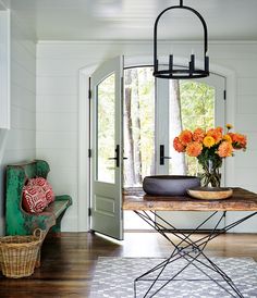 a dining room table with flowers on it in front of an open door to the outside