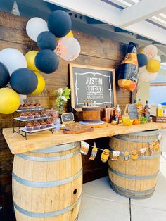 a wooden table topped with lots of food next to two barrels filled with drinks and desserts