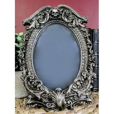 an ornate silver frame sitting on top of a table next to a book and plant