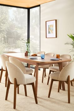 a dining room table and chairs in front of a large window