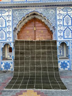 an intricately designed area with blue and white tiles on the walls, in front of a wooden door