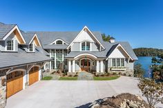 a large house sitting next to a lake with lots of windows on the side of it