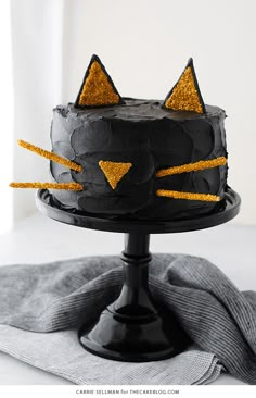 a black cake with gold glitter cats on it and a gray towel next to it