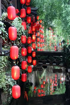 many red lanterns hanging from the side of a bridge