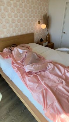 an unmade bed with pink sheets on it