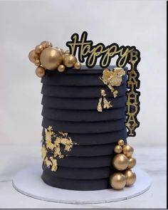 a black and gold birthday cake on a white plate