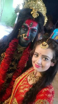 two women dressed in costumes posing for the camera with their faces painted red and gold