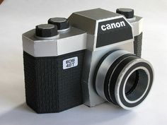 an old fashioned camera sitting on top of a white table next to a black and silver lens