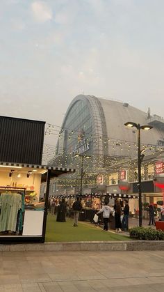 people are walking around in front of a large building with lots of lights on it