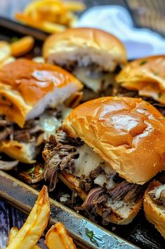 several pulled pork sandwiches with cheese and french fries on a baking sheet, ready to be eaten