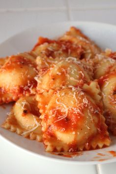 pasta with sauce and parmesan cheese in a white bowl on a tile counter