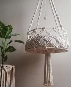 a white macrame hanging basket next to a potted plant