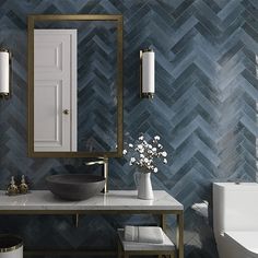 a bathroom with blue and white tiles on the walls, a gold framed mirror, a black bowl sink and a toilet