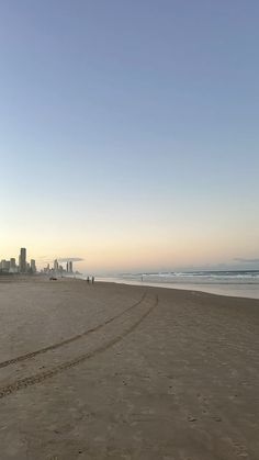 a person is flying a kite on the beach at sunset with buildings in the background