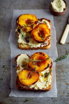 two pieces of bread with peaches and cream on them sitting on top of a piece of parchment paper