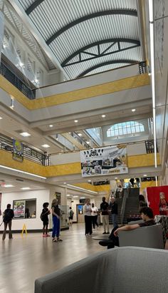 people are walking around in the lobby of a shopping mall, with yellow and white walls