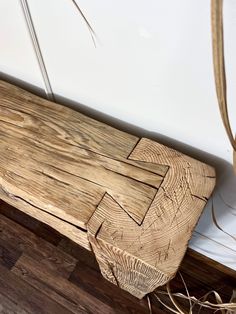 a wooden bench sitting on top of a hard wood floor next to a white wall